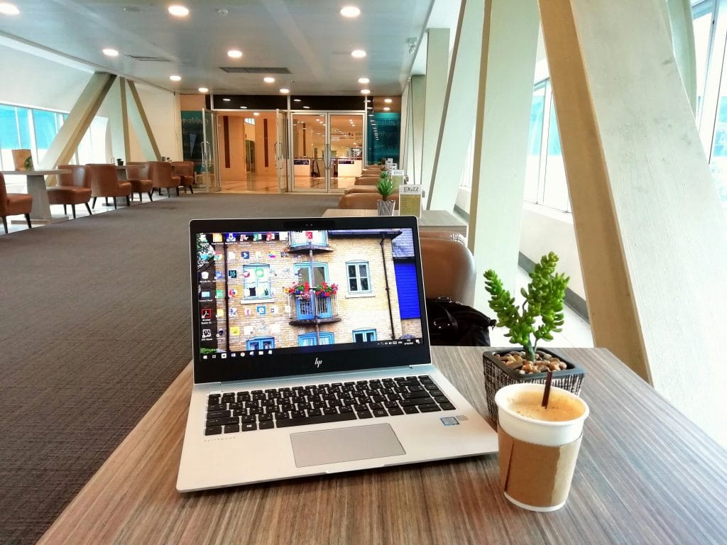 Contemporary office lounge featuring a laptop, coffee cup, and plant on a table with stylish interior design.
