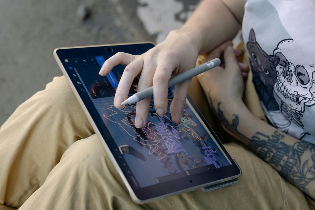 Person drawing digital art on a tablet using a stylus pen, showcasing creativity and technology.